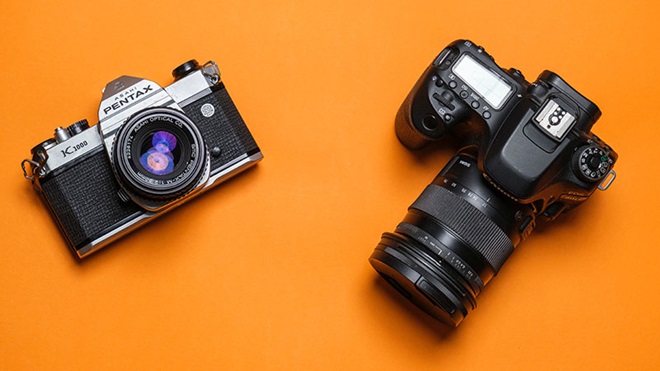 uma câmara digital canon e uma câmara analógica pentax num fundo laranja 