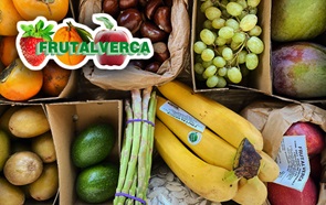 Vista de cima de diversas pequenas caixas e sacos de papel contendo várias frutas. Da esquerda para a direita e de cima para baixo: dióspiros, castanhas, uvas, mangas, kiwis, abacates, espargos, pevides e bananas. Em cima, à esquerda, o logótipo da Frutalverca, que consiste na inscrição "Frutalverca", a verde, aplicada sobre a fotografia do recorte de um morango, uma laranja e uma maçã redimensionados para se apresentarem com o mesmo tamanho.