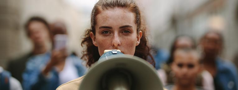 Rapariga com megafone na mão, como se fosse fazer uma queixa na plataforma Reclamar da DECO PROTeste.