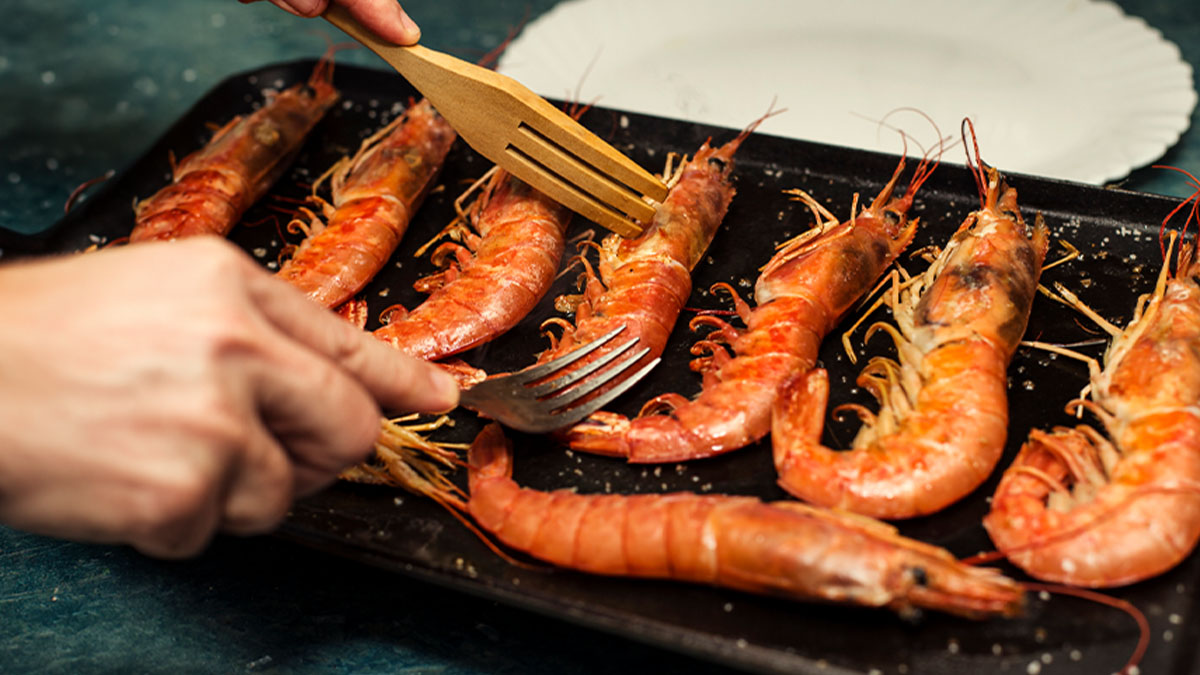 Pessoa a grelhar gambas na chapa
