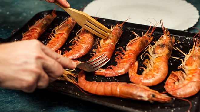 Pessoa a grelhar gambas na chapa