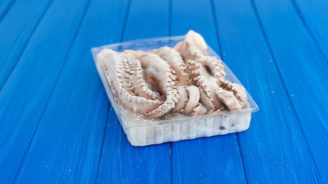 Embalagem de polvo congelado numa mesa de madeira azul