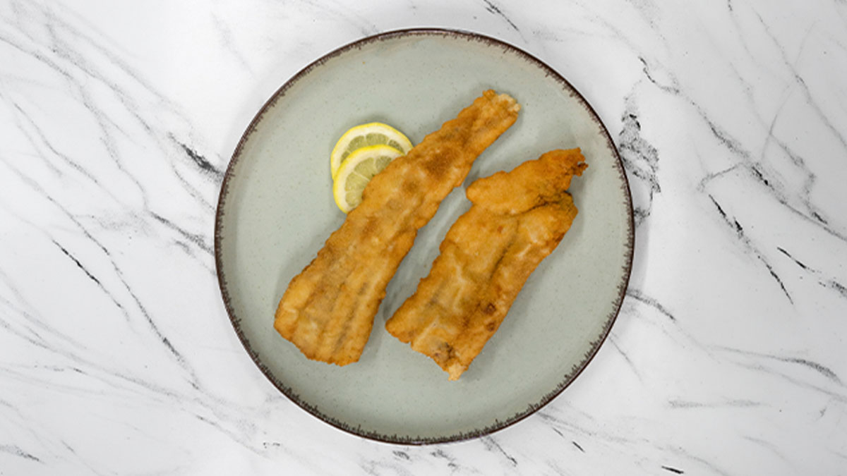 Filetes fritos num prato, vistos de cima, sobre um tampo de mármore