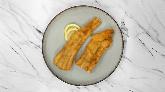 Filetes fritos num prato, vistos de cima, sobre um tampo de mármore