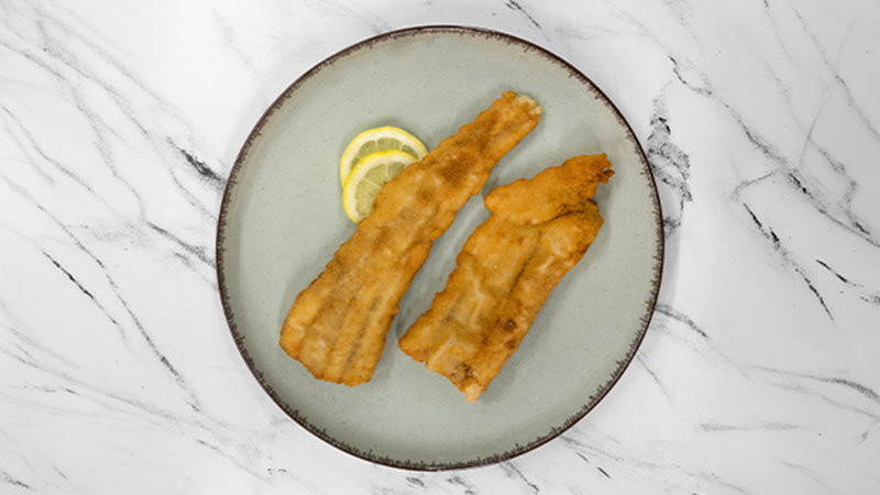 Filetes fritos num prato, vistos de cima, sobre um tampo de mármore