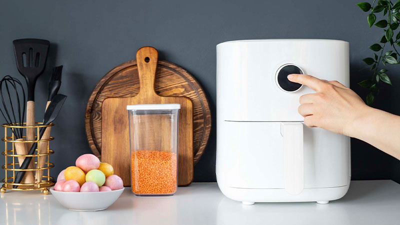 Bancada de cozinha com air fryer e uma taça com ovinhos de páscoa