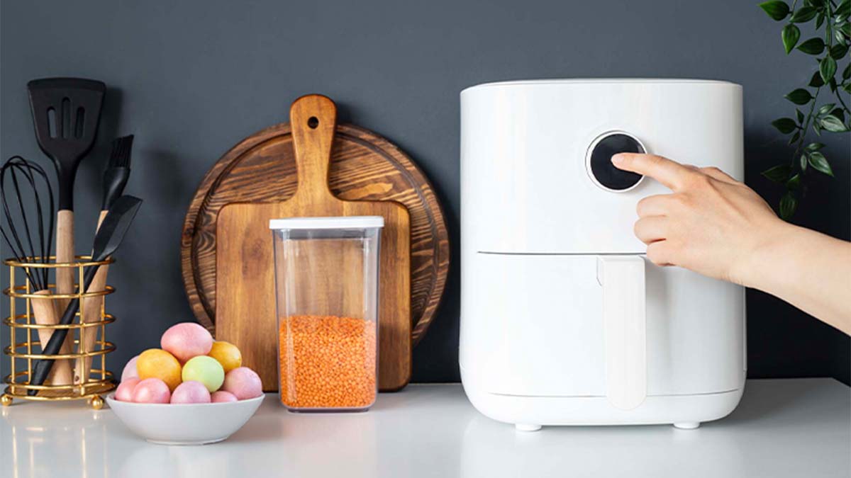 Bancada de cozinha com air fryer e uma taça com ovinhos de páscoa