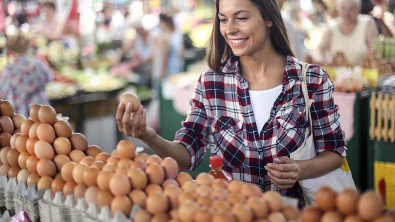Mulher a escolher ovos num mercado ao ar livre.