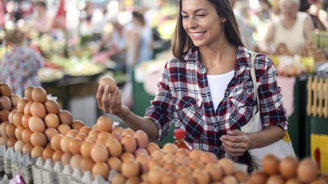 Mulher a escolher ovos num mercado ao ar livre.