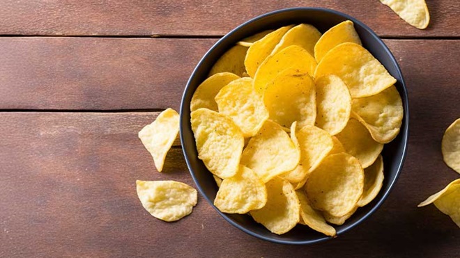 Taça de batatas fritas vista de cima, sobre um fundo de madeira
