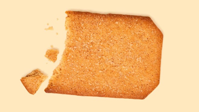 Bolacha de canela partida vista de cima sobre um fundo creme