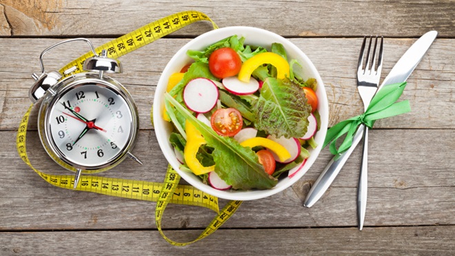 taça com salada, fita métrica e talheres usados no controlo de peso