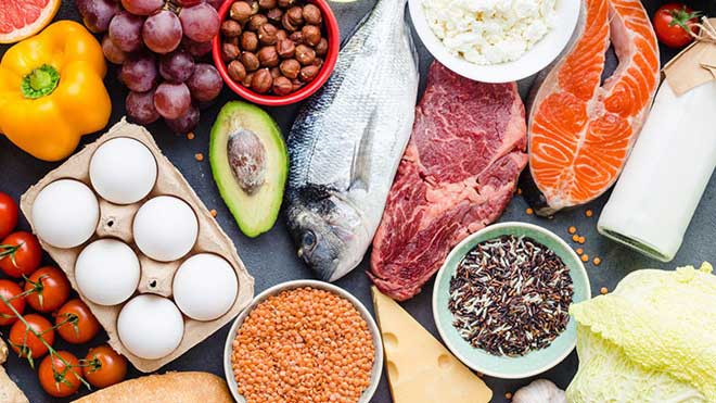 mesa com tomates cherry, pimentos, ovos, uvas, abacate, peixe, carne, salmão, frutos secos