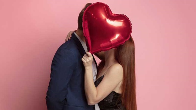 namorados beijam-se tapados por um balão em forma de coração
