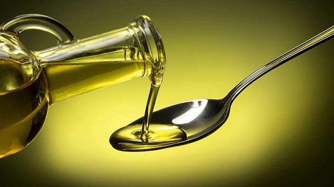 Garrafa de azeite a verter para uma colher