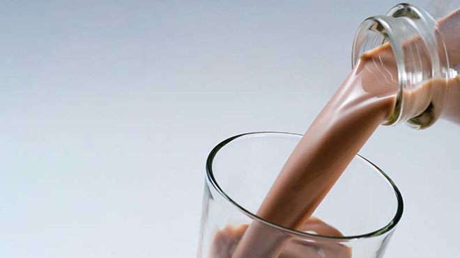 Garrafa a deitar leite com chocolate para um copo