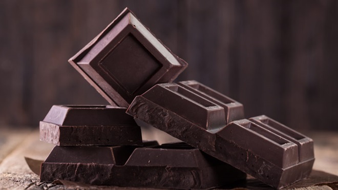 Pedaços de chocolare preto empilhados em cima de uma mesa de madeira