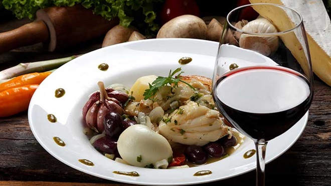 Prato de bacalhau com copo de vinho tinto