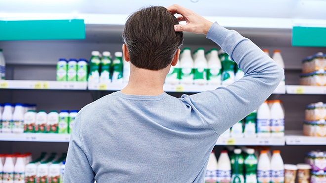 Num supermercado, um consumidor hesita perante o expositor dos lacticínios.