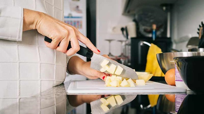 pessoa a cortar alimentos numa tábua