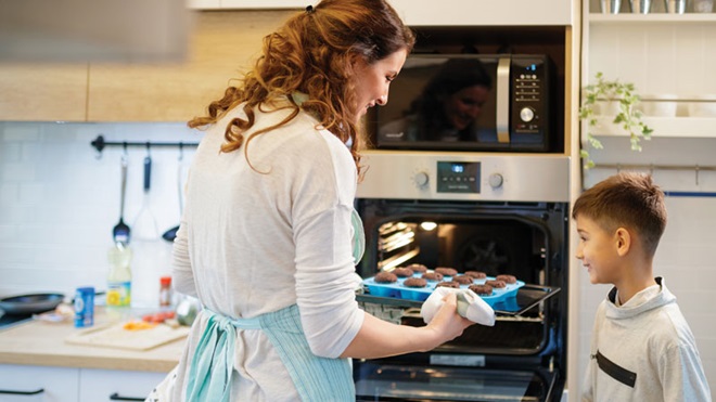 Mãe e filho a colocarem bolos no forno em forma de silicone