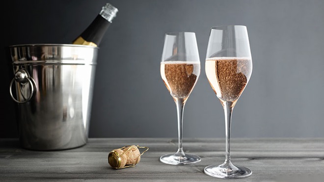copos com espumante rosé, rolha e garrafa na mesa
