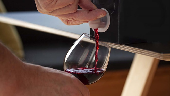 Grande plano de mão a encher um copo com vinho tinto a partir da torneira de bag in box 