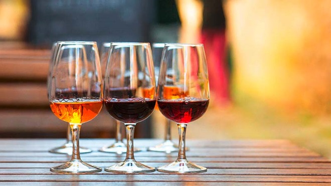 Copos de vinho do porto de várias tonalidades em cima de uma mesa de madeira