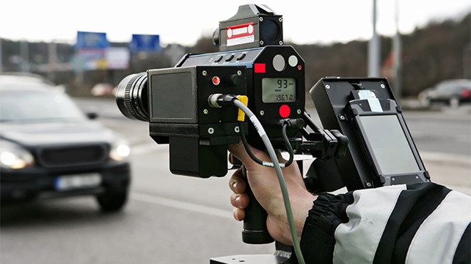Agente da autoridade com radar de velocidade portátil a apontar para o trânsito