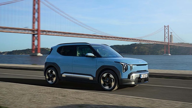 Kia EV2 na estrada ao lado do rio Tejo e com a Ponte 25 de Abril de fundo.