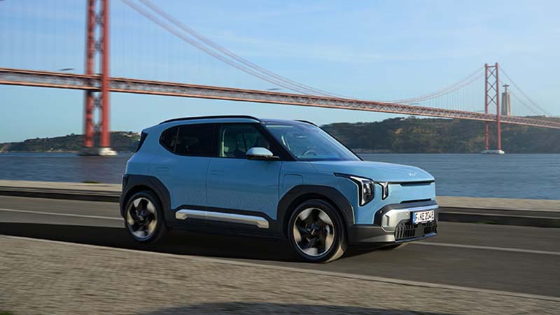 Kia EV2 na estrada ao lado do rio Tejo e com a Ponte 25 de Abril de fundo.