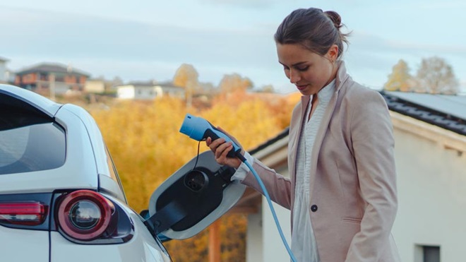 Mulher a carregar um carro elétrico num posto de carregamento