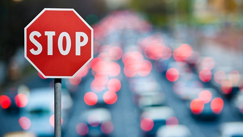 Sinal de STOP com estrada com carros em engarrafamento ao fundo
