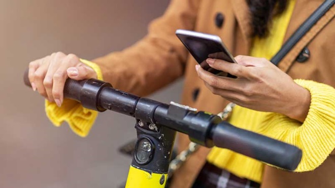 Mulher na trotinete a consultar telemóvel