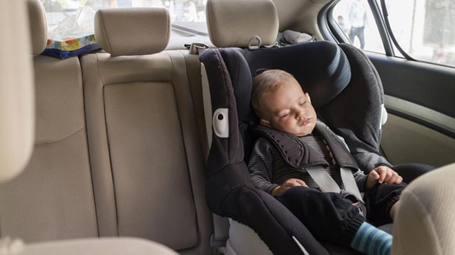 Criança a dormir na cadeirinha de bebé no bancop de trás do carro 