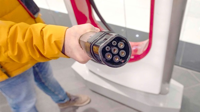 Pessoa a segurar carregador de carro elétrico