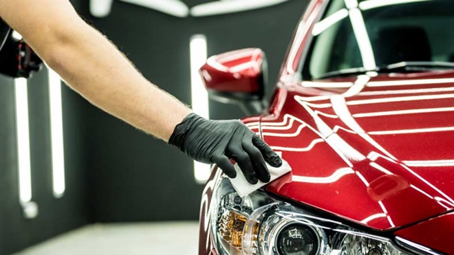 Grande plano de carro a ser limpo por mãos profissionais - alusão a serviços de oficina