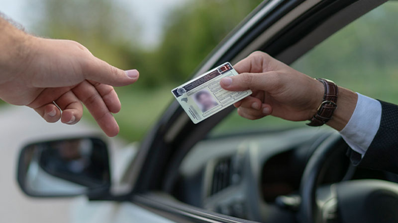Homem a mostrar carta de condução brasileira a polícia