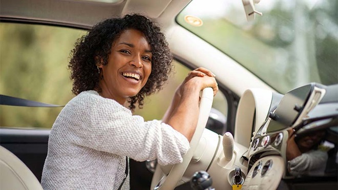 Mulher dentro de carro no lugar do condutor, a sorrir para a câmara