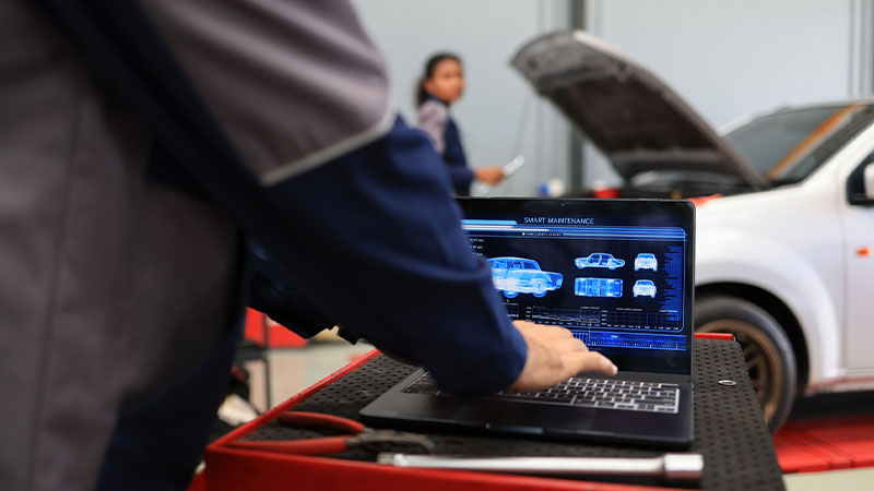 Mecânico a verificar ferramenta de diagnóstico automóvel em oficina