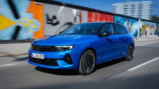 Opel astra electric azul a andar na cidade com uma parede grafitada atrás