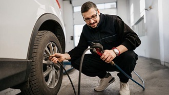 Homem verifica o pneu do carro numa oficina
