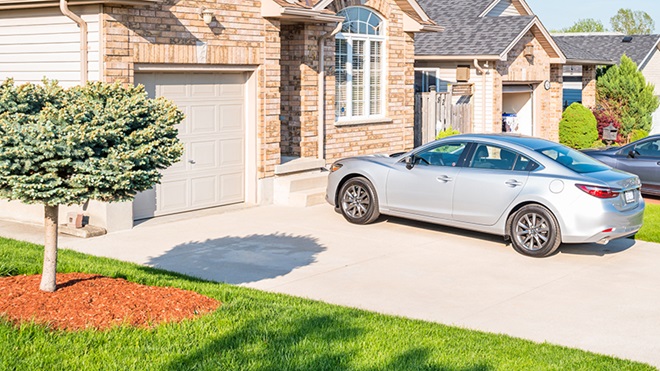 carro à porta de uma garagem parado 