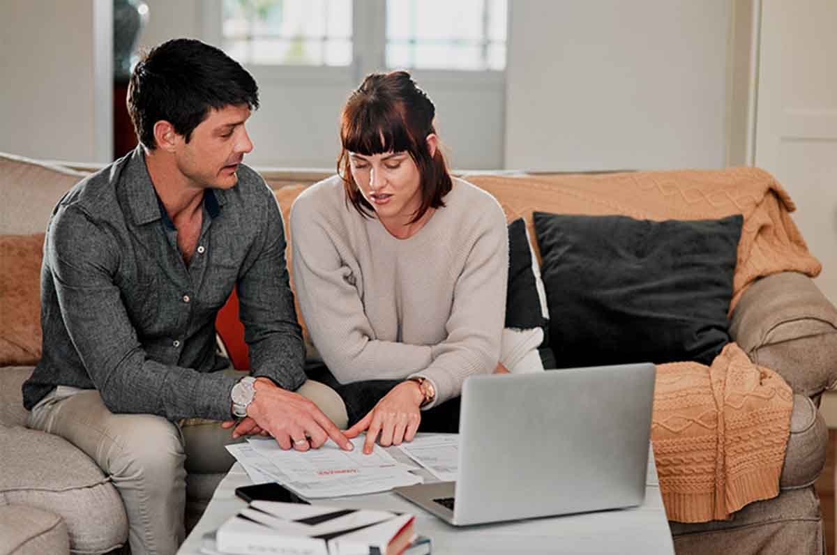 casal sentado no sofá em casa enquanto analisar finanças pessoais