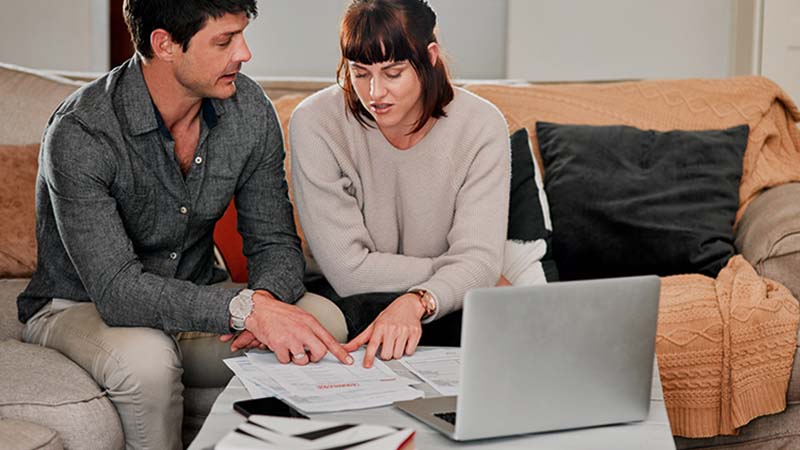 casal a analisar documentação com computador portátil