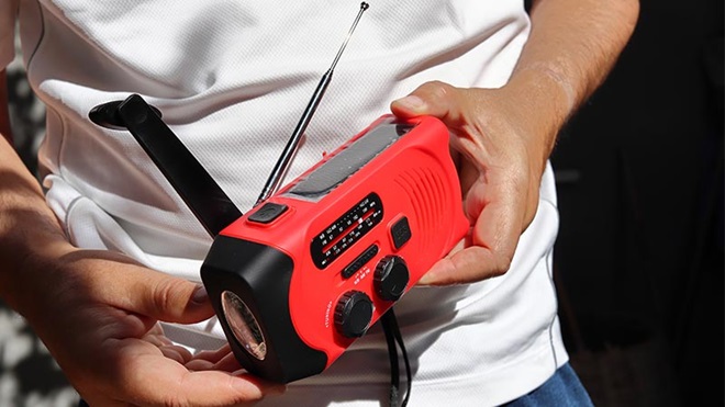 Mãos a segurar um pequeno rádio portátil