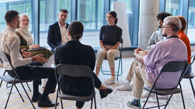 Grupo de pessoas sentadas a conversar numa sala comunitária, num ambiente descontraído.