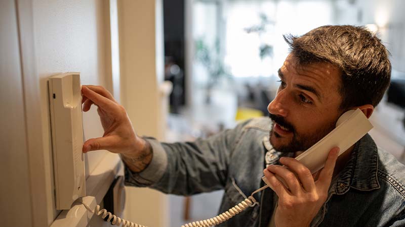 Homem a usar intercomunicador em apartamento
