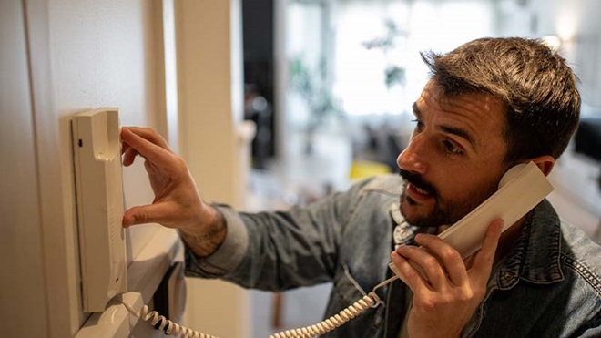 Homem a usar intercomunicador em apartamento