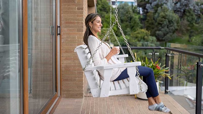Mulher sentada numa cadeira de baloiço na varanda de casa